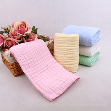 Soft pink six-layer cotton muslin baby blanket draped over a woven basket in a bright nursery