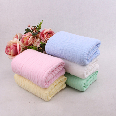 Folded stack of six-layer cotton muslin baby blankets in pink, yellow, white, blue and mint